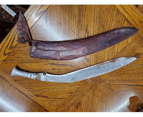 A KUKRI IN A LEATHER SCABBARD, THE HANDLE OF ALUMINIUM, THE OVERALL LENGTH. 73cms.