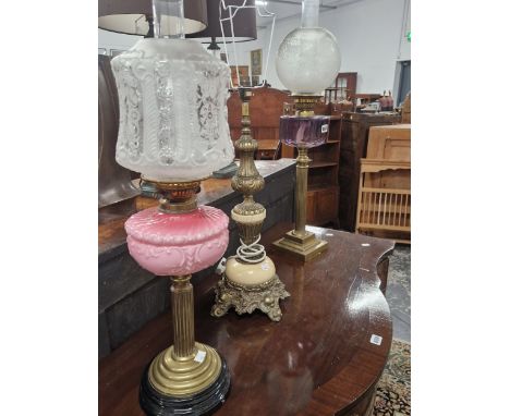 TWO OIL LAMPS WITH COLOURED GLASS RECEIVERS ON REEDED BRASS COLUMNS AND TOGETHER WITH A MARBLE AND GILT METAL TABLE LAMP