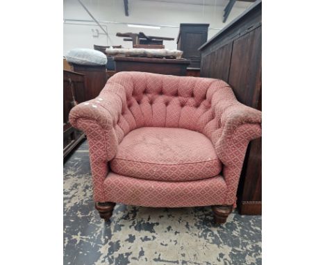 A TUB ARMCHAIR WITH A ROUNDED BUTTON UPHOLSTERED BACK, THE TURNED MAHOGANY FRONT LEGS ON BRASS CASTER FEET
