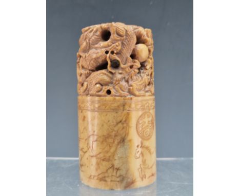 A CHINESE PINK/BROWN SOAPSTONE CYLINDRICAL SEAL PIERCED AND CARVED WITH DRAGONS CHASING A PRECIOUS PEARL, THE BASE CUT WITH T