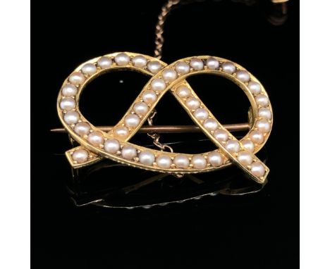 AN ANTIQUE GOLD AND SEED PEARL SWEETHEART LOVERS KNOT, ALSO KNOWN AS A STAFFORD KNOT BROOCH. THE REVERSE WITH HIDDEN FINENESS