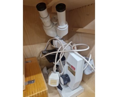 A CASED LOMO BINOCULAR MICROSCOPE WITH AN ELECTRIC LIGHT SOURCE AND SOME ACCESSORIES AND INSTRUCTIONS