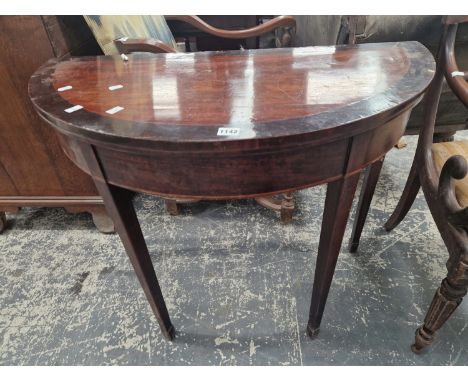 A GEORGE III EBONY CROSS BANDED MAHOGANY DEMILUNE GAMES TABLE OPENING ON A DOUBLE GATE