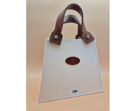 A TABLE LAMP MODELLED AS A CREAM COLOURED HANDBAG WITH BROWN LEATHER HANDLES.   H 37cms.