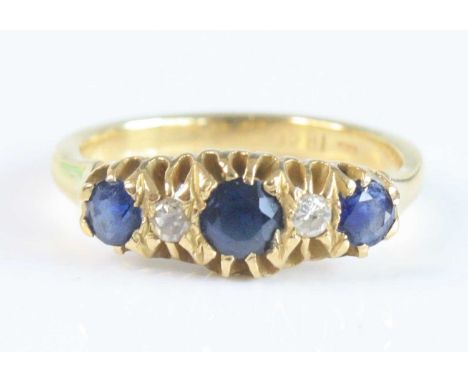 A yellow metal, sapphire and diamond five-stone half-hoop eternity ring, featuring three graduated round faceted sapphires in