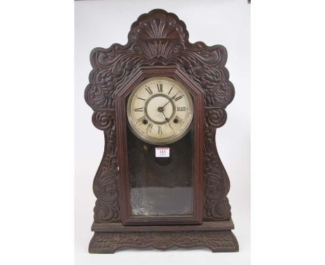 An early 20th century carved and stained walnut American shelf clock, the paper dial showing Roman numerals and stating 'Manu