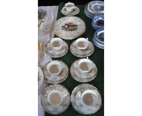 A collection of hunting scene cups and saucers and four dinner plates.