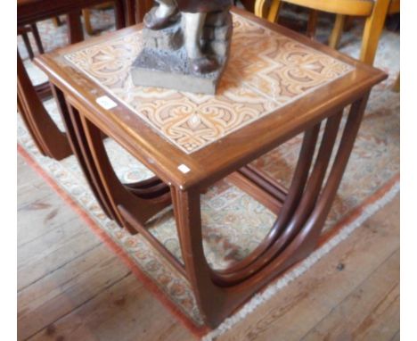 A 1970's set of three teak G-plan nesting tables, the largest with four tile decoration, each on stylized supports, the large