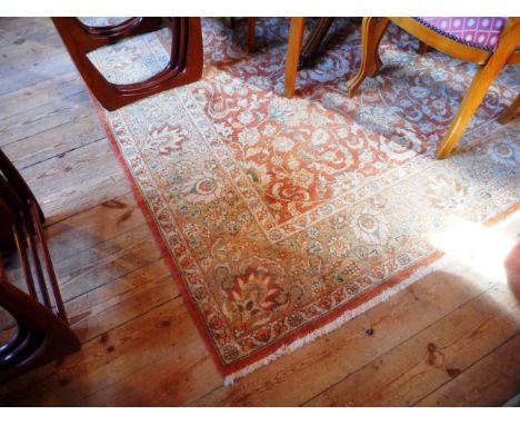 A hand made woollen Kashan carpet, the central panel decorated with floral and leaf patterns on an orange ground, the border 