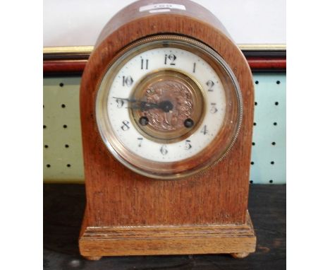 A mid-20th century oak cased mantle clock, the face with Arabic numerals, lining a copper central panel depicting Roman figur