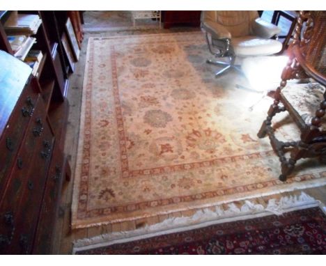 A Pakistan 100% wool pile carpet, the central panel decorated with stylized floral and leaf forms, the border similarly decor