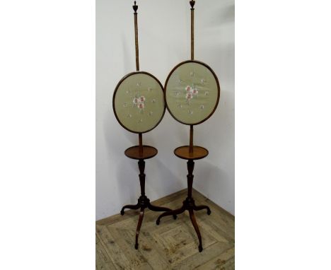 Pair of 19th/20th C mahogany pole screens with circular shelf under oval panels depicting floral needlework detail 