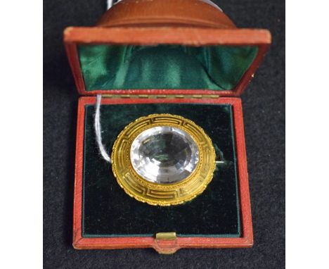 A late 19th century oval brooch, central oval faceted rock crystal within a stepped yellow metal seven layer rope twist, chai