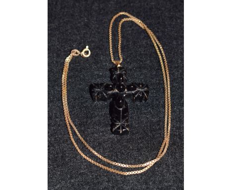 A carved jet cross pendant, five central oval raised undulation, within carved eight point cross terminals, suspended from a 