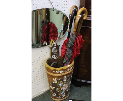 A painted wooden stick stand with a selection of umbrellas etc