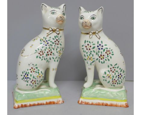 A pair of Staffordshire cats, decorated with enamel paints, a/f, 18cm 