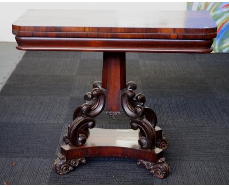 Early Victorian rosewood card table with fold over swivel top supported by a scroll carved base with faceted column, 92cm wid