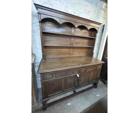A 1.57m antique oak and strung two part dresser with arcaded two shelf open plate rack over a base with two frieze drawers an