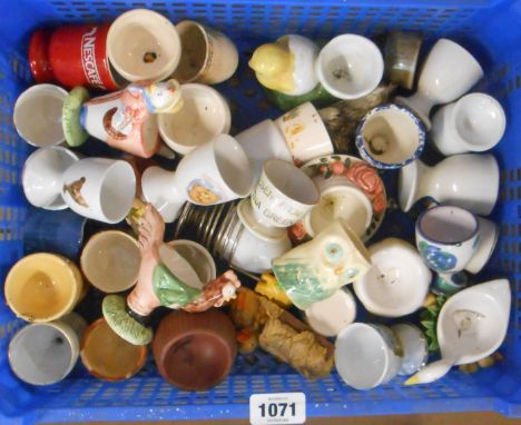 A small crate containing a quantity of novelty egg cups including Carlton Ware 'Feet' example, 'Wallace and Gromit', etc.