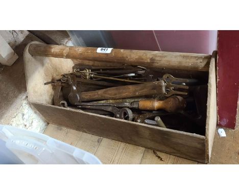 A wooden toolbox containing assorted old tools including spanners, screws drivers, etc.