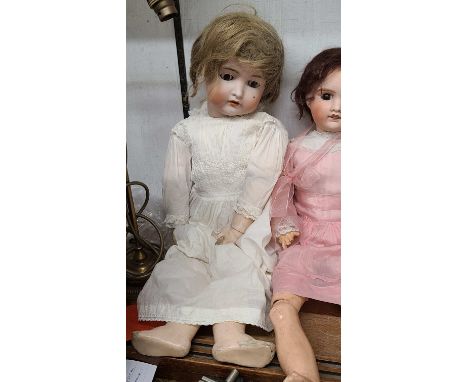 An antique German porcelain headed doll marked for Bruno Schmidt with a hair, glass eyes and composition body, wearing a lace