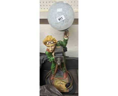 A resin table lamp, depicting a stylish photographer, with glass globe shade