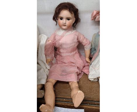 An early 20th Century French porcelain headed doll with fixed glass eyes, composition body, brown mohair wig and original clo