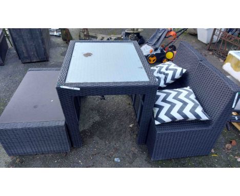 A modern black woven garden furniture set comprising a glass topped table, low table and two chairs