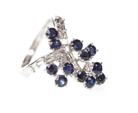 BLUE GEM SET AND DIAMOND RING, the crossover bezel set with round blue gems and round brilliant cut and baguette cut diamonds
