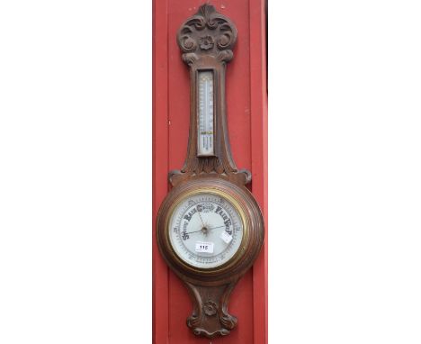 A carved oak aneroid wall barometer, banjo shaped