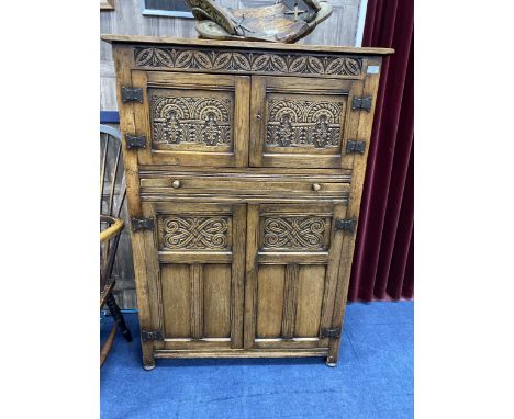 A MODERN OAK CUPBOARD, with carved panel doors, 131cm high, 92cm wide