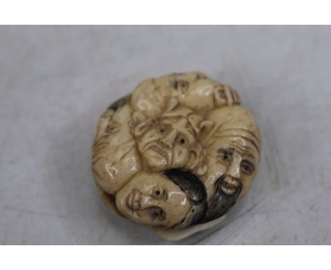 A reproduction faux ivory netsuke, moulded as four faces, 4cm