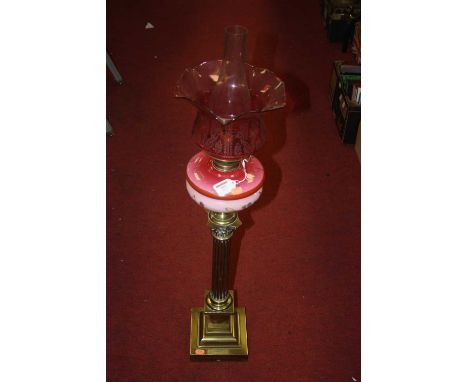 A Victorian pedestal oil lamp, having a cranberry tinted etched glass shade above a pink glass font with floral decoration, r