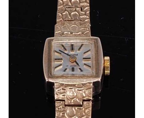 A 9ct yellow gold lady's manual wind Accurist wristwatch, having a square silver baton dial and integral textured flatlink br