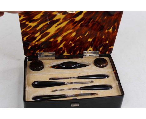A George V faux tortoiseshell lady's manicure set, the case of rounded rectangular form with silver hinges, contents to inclu