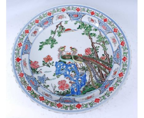 A Chinese Republic period stoneware charger, enamel decorated with peacocks amidst flowering bamboo and borders, six characte