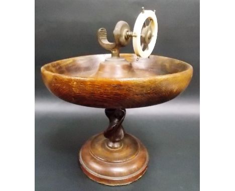 A nutcracker in the form of a ship's wheel with an oak bowl and on oak barley twist pedestal.