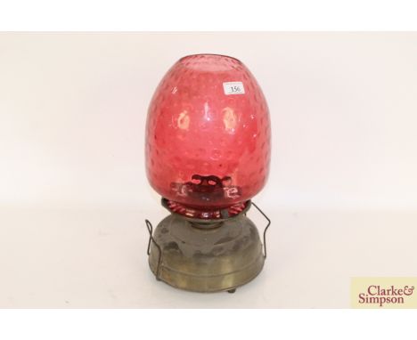 A large brass oil lamp with dimpled ruby glass shade 
