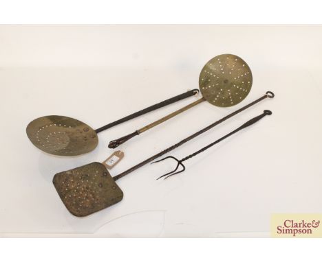Two antique brass cream skimmers, an iron cream skimmer and a toasting fork