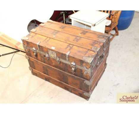 A large metal bound wooden travelling trunk with leather side carrying handles 