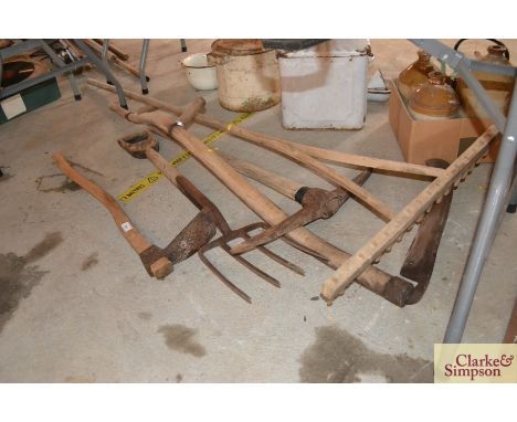 A vintage wooden rake, a scythe, a fork, a pick axe and an adze