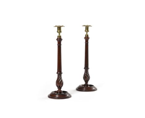 A PAIR OF GEORGE III MAHOGANY LIBRARY CANDLESTICKS  CIRCA 1800  Floral brass nozzles and pans above fluted stems with spiral 