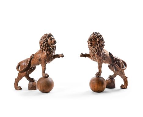 A LARGE PAIR OF CARVED OAK LIONS  19TH CENTURY  Carved in opposing rampant form, each with one front foot raised on a sphere,