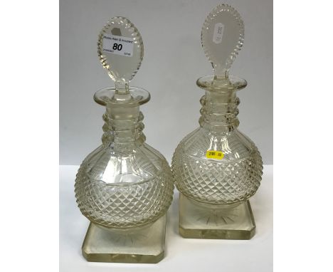 A pair of 19th Century cut glass decanters of onion form with faceted three collar neck and pear shaped stoppers, raised on s