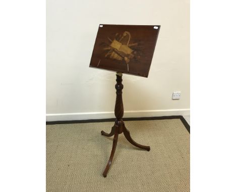 A modern mahogany and marquetry inlaid adjustable music stand, the main panel decorated with symbols of music on a wrythen ca