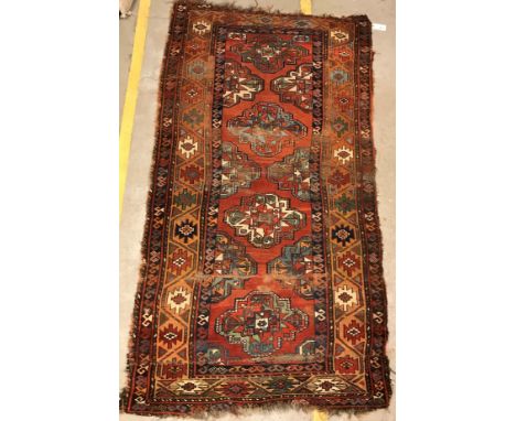A Caucasian rug, the central panel set with repeating medallions on a red ground, within a stepped red, blue and orange geome
