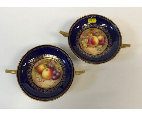A pair of Royal Worcester circular two-handled pedestal dishes, blue and gilt decorated, the centre panels painted with fruit