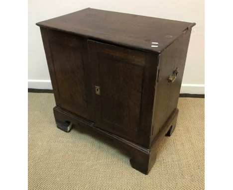 An 18th Century oak dwarf cupboard, the plain top with moulded edge over two panelled doors enclosing three adjustable shelve