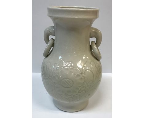 A Chinese cream glazed pottery vase with relief floral decoration to the baluster body and elephant head and ring handles, ra