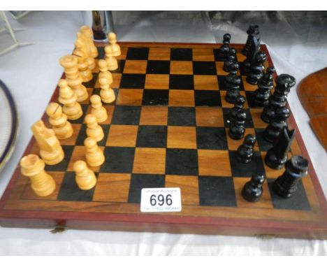 A cased wooden chess set with folding board